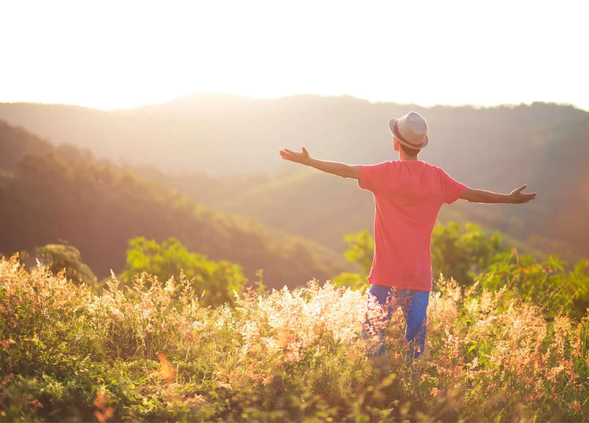 A person standing in the Utah foothills at sunset with arms open